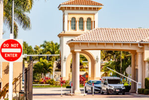Gated entrance of a residential community association with security gate and landscaped surroundings.